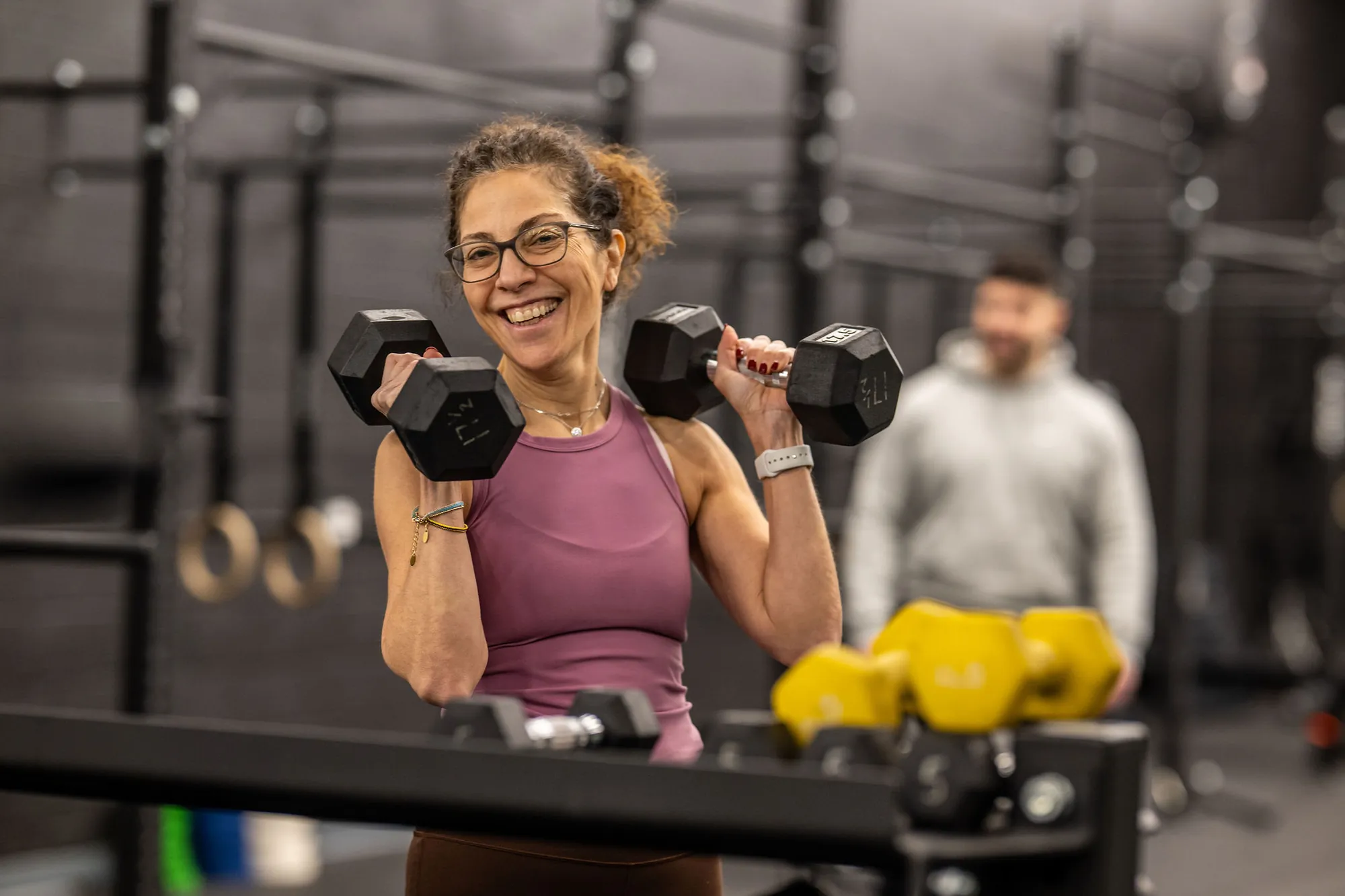 A LIFT member smiling mid-set with dumbbells